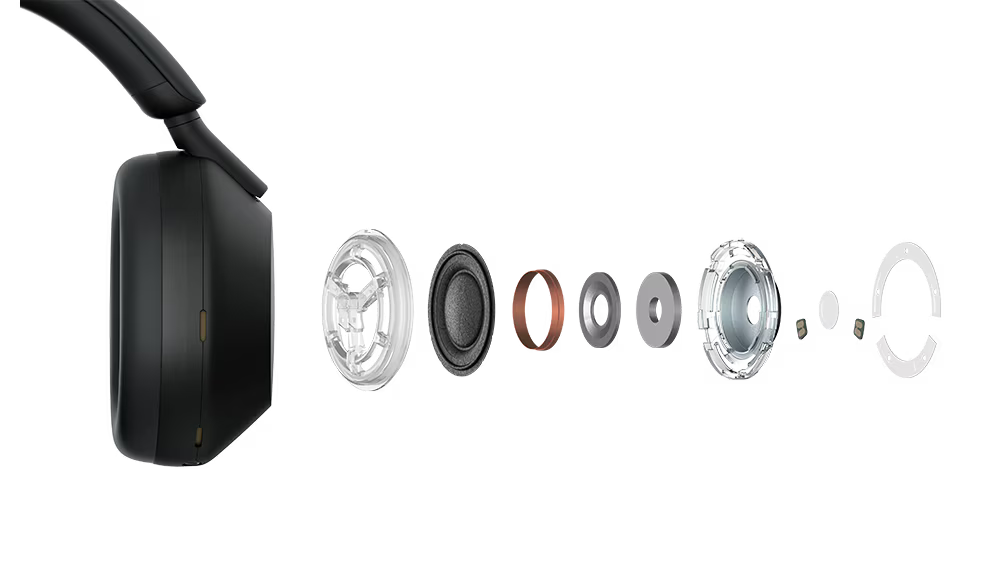 A person wearing the Sony WH-1000XM5 headphone while working on a laptop in a busy coffee shop to demonstrate industry-leading noise cancellation.